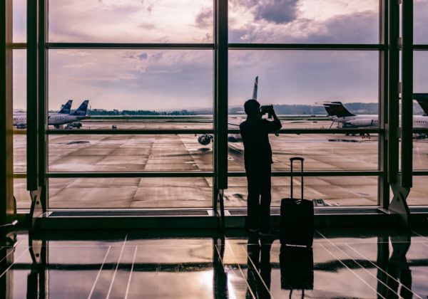 A silhouette of a man taking photos at the floor-to-ceiling window in an airport