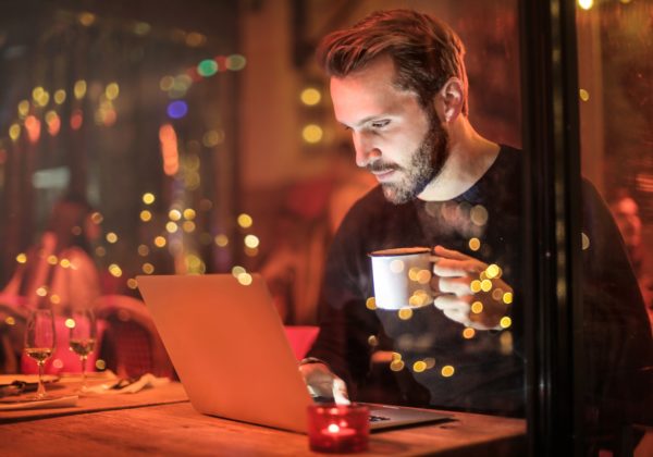Renter's insurance: a man is working on his laptop drinking coffee.