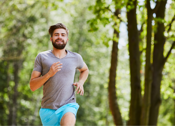 man running and smiling surrounded by trees